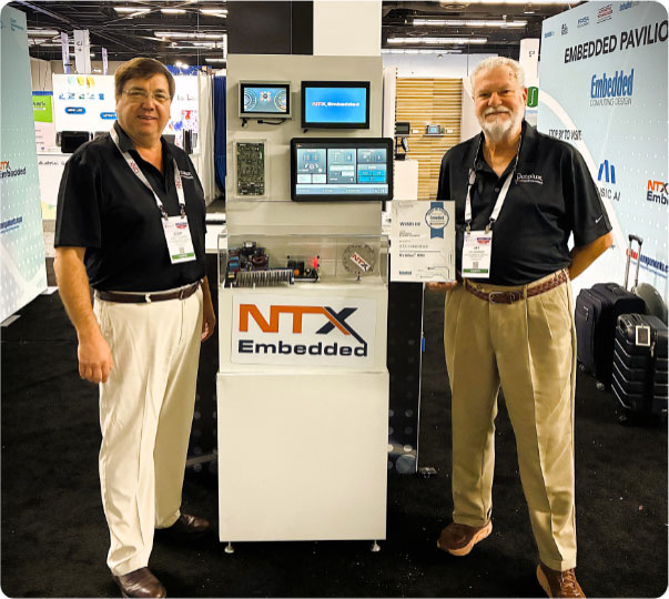 two men standing proudly next to award presented to NXT Embedded